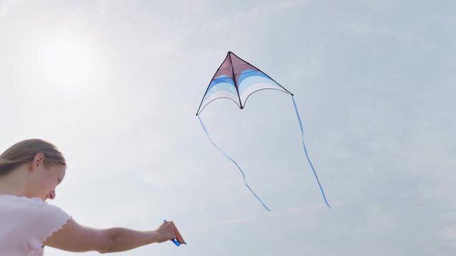 The girl looks up at the flying kite slow motion rear view close-up from below dynamic camera movement