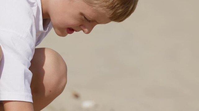 A boy is digging in the sand on the beach slow motion close-up tilt camera movement