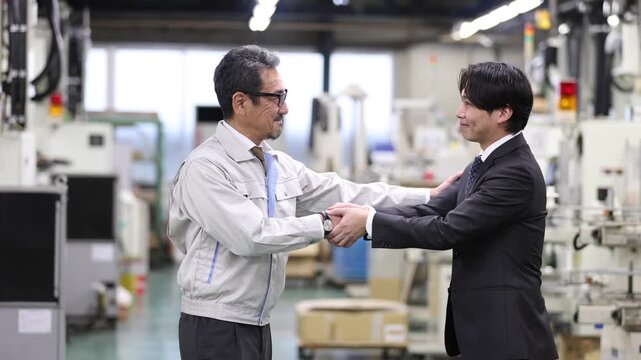 工場内で銀行担当者と握手を交わす製造業の経営者・企業融資契約の成立と資金調達