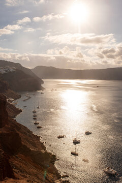 Sunlight glinting over the caldera and anchored boats in the Aegean