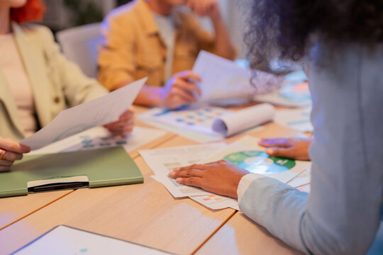 Close up of business team hands reviewing ESG sustainability reports and green charts on table during corporate meeting about environmental strategy