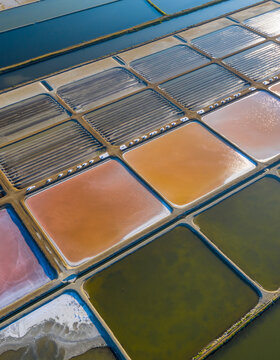 Aerial top view of colorful salt evaporation ponds salt pans with vibrant water fields during salt production