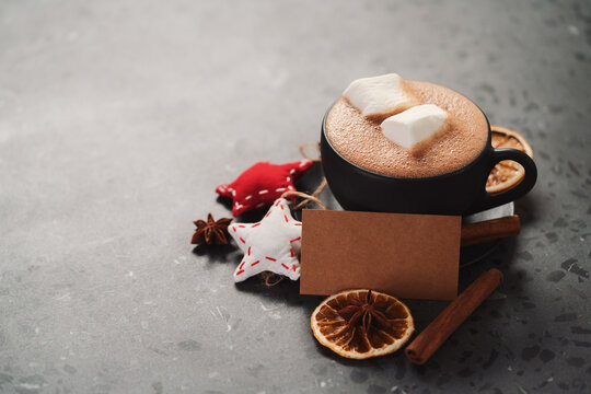 Hot chocolate in a black cup with christmas decorations and paper card