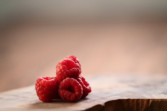 ripe raspberry on a olive wood board with copy space