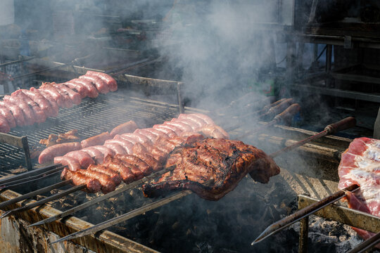 Meat and sausages grill on skewers over smoky charcoal outdoors