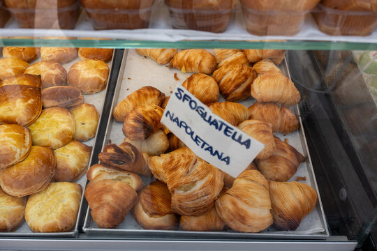 traditional Italian Sfogliatelle pastries displayed in an Italian bakery case with a handwritten label