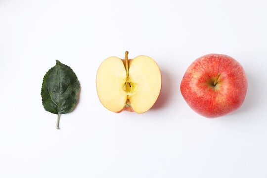 Whole and sliced ​​red apples with green leaf on white background, top view