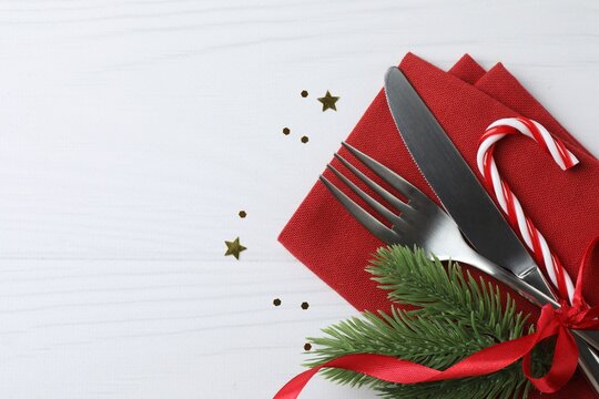 Top view of Christmas table setting with cutlery and festive decor on white background. Copy space