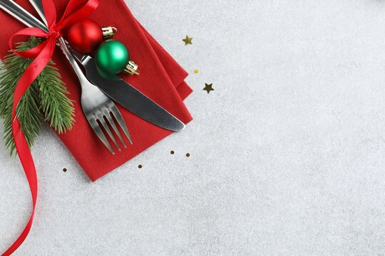 Christmas table setting with cutlery and festive decor on grey background. Space for text, top view