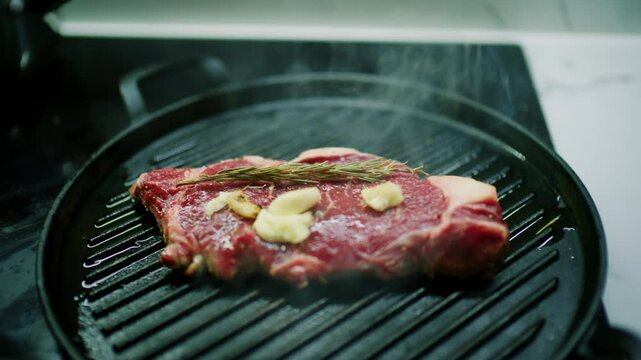 Beef steak topped with butter, garlic and rosemary sizzling on a round cast iron grill pan, French Riviera, France.