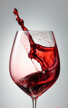 Wine glass with red liquid frozen in movement.