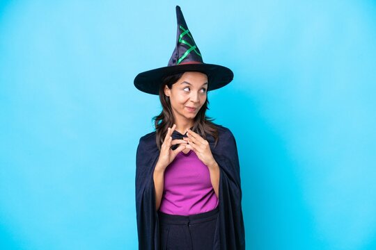 Young hispanic woman dressed as witch over isolated background scheming something