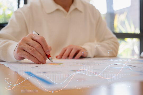 Businessman using pen and paper report while analyzing data at office, Financial analysis or business evaluation concept