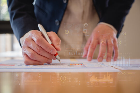 Businessman using pen and paper report while analyzing data at office, Financial analysis or business evaluation concept