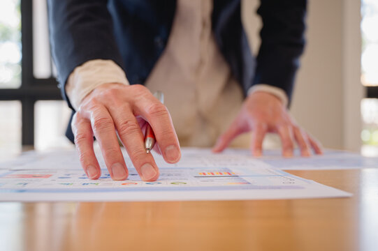 Businessman using pen and paper report while analyzing data at office, Financial analysis or business evaluation concept