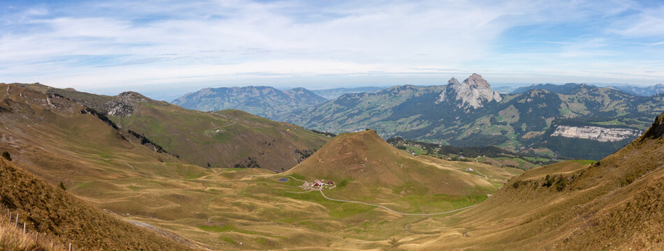 Wide panoramic view of scenic mountain peaks and alpine valley under blue sky
