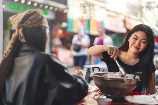 Two young asian woman sisters enjoy eaiting street food thai barbeque menu dinner meal