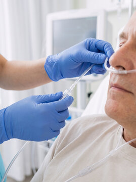 close-up of a respiratory nurse fitting a soft nasal oxygen cannula on an adult patient and adjusting the tubing for comfort, gloved hands checking the connector and line placement