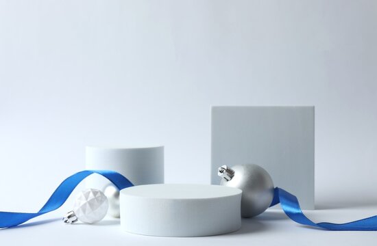 Christmas composition with empty podium, blue riboon and festive baubles on white background 