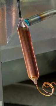 Refrigeration Technician Brazes Copper Filter Connection. Soldering copper filter drier into refrigerator cooling circuit with torch heat applied at tubing connection. 