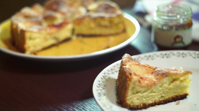 Apple pie slice closeup vintage plate. Rack focus baked charlotte jam jar table.