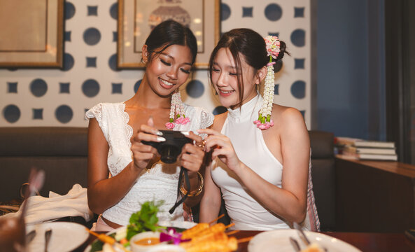 Two young asian women using digital camera foodie enjoy asia Thai food in authentic restaurant