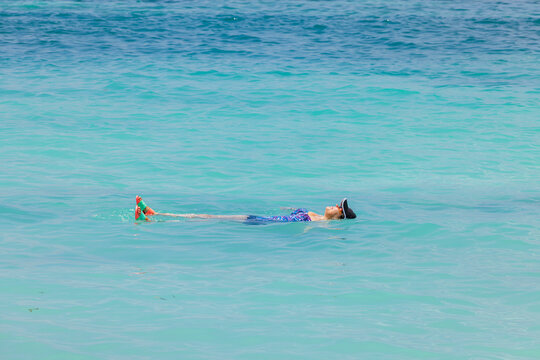 Beautiful view of woman floating on her back in turquoise waters of Caribbean Sea. Aruba.