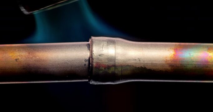 Torch Heating and Brazing Copper Pipe Joints. Gas torch heats copper pipe joints for brazing changing metal from warm copper to glowing colors. Plumbing repair process. 