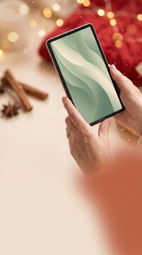 Recipe browser holding a tablet beside cinnamon sticks, star anise and warm golden bokeh