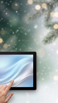 Online shopper touching a tablet screen with a soft blue wave against frosted pine and snowy bokeh