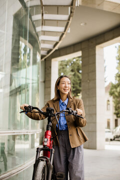 Korean woman pauses with her electric bike beneath a modern walkway