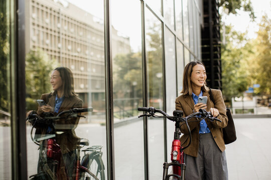 Korean woman pauses beside her electric bike in warm city light