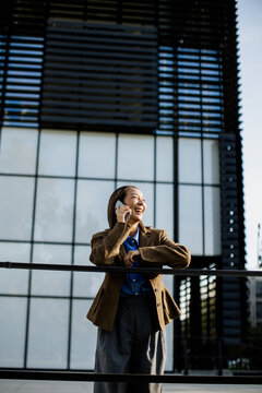 Woman talks on a phone near a modern building in a city during the daytime
