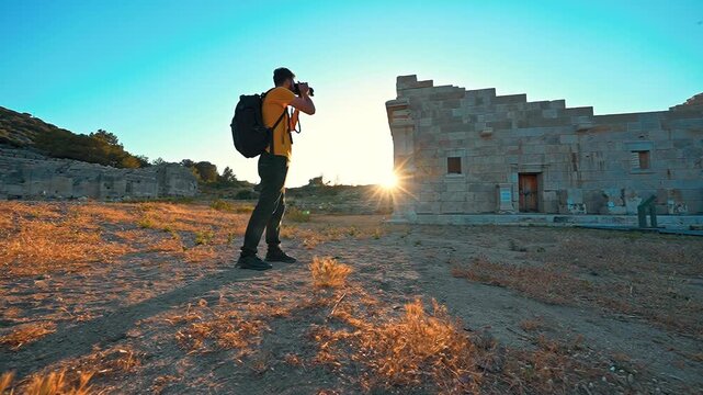 Patara Ancient City in Antalya features a photographer capturing historic stone ruins at sunset, illuminated by warm golden light.