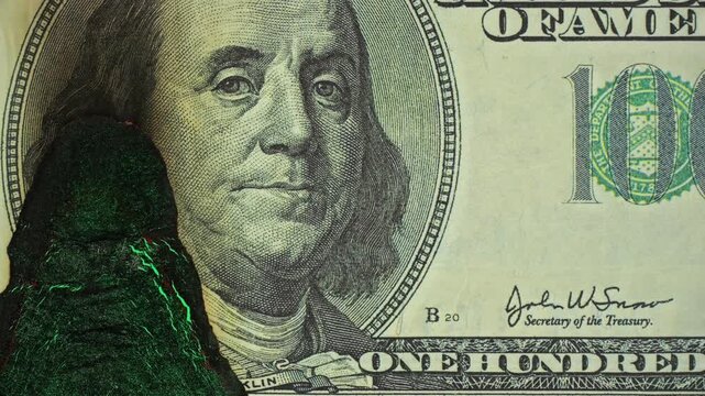 Dollar Bill with Benjamin Franklin Burns on Green Screen. Macro view follows charred paper as it smolders and burns away for chroma key compositing. Smoldering Currency Portrait with Chroma Key.