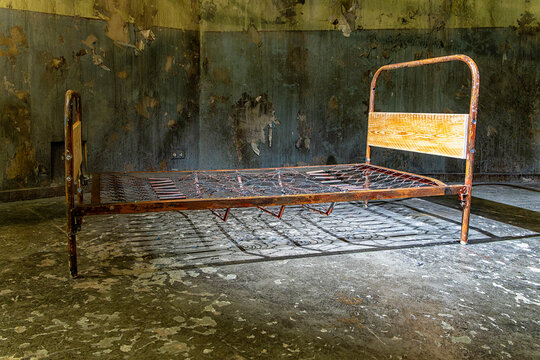 Altes, rostiges Metallbett mit einem geflochtenem Federkern und h&ouml;lzernen Kopfteil, das in einem verfallenen Raum steht, Berlin, Deutschland
