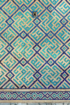 Geometric glazed tile mosaic on the wall of Sher Dor Madrasah at Registan Square in Samarkand. Ideal for backgrounds, cultural publications, and architectural design references.
