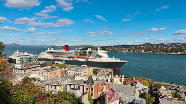 Wide shot of a large transatlantic ocean liner docked at the port of Quebec City, Canada, the majestic cruise ship stands near historic lower town buildings along the St. Lawrence River.