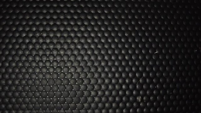 Seamless black textured rubber mat surface with round dotted grips pattern macro