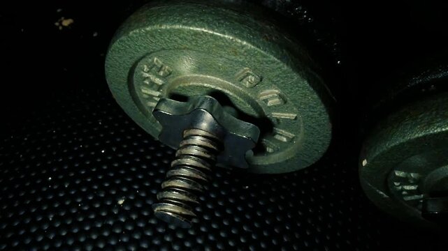 Heavy cast iron dumbbells with spinlock collars on black rubber gym floor closeup