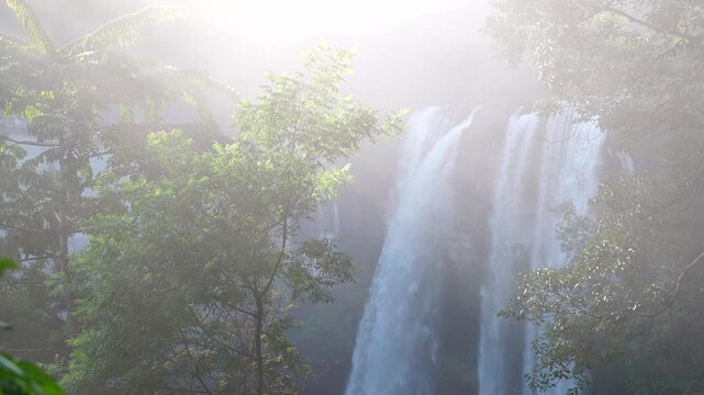 Sun Rays Shining Through Misty Forest Waterfall