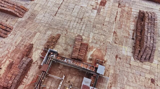 Workers stand beside metal platforms and stacked materials on a broad stone excavation site, with brick structures and exposed layers visible during the day.