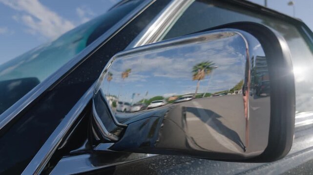 Palm trees, blue sky and a person filming reflected in the chrome side mirror of a classic car, French Riviera, France.