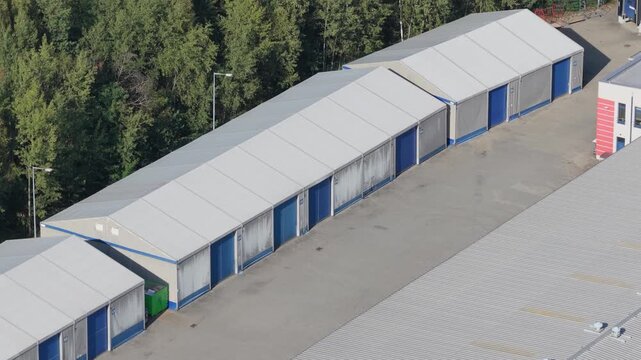 Aerial view of a row of self storage units in an industrial area next to a forest