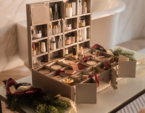 Luxury beauty advent calendar opened on a sophisticated vanity table, 24 small elegant compartments containing generic skincare and beauty products, candles, satin ribbon