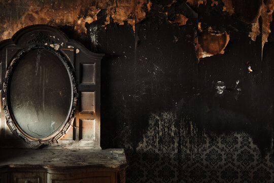 Burned interior with shattered mirror and soot-covered wall