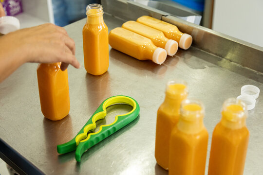 Worker fill orange juice bottle on stainless steel table
