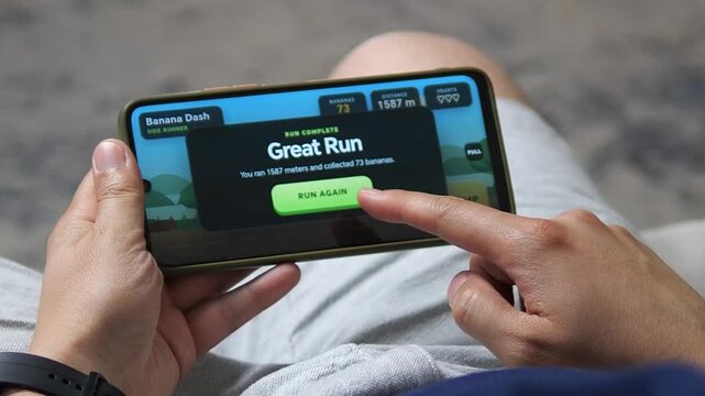 Player completes a colorful mobile runner game on a smartphone, reaching a high score after collecting fruit and overcoming obstacles in a fast casual gaming session.