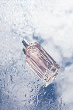 Perfume bottle on rain covered glass with cloudy sky