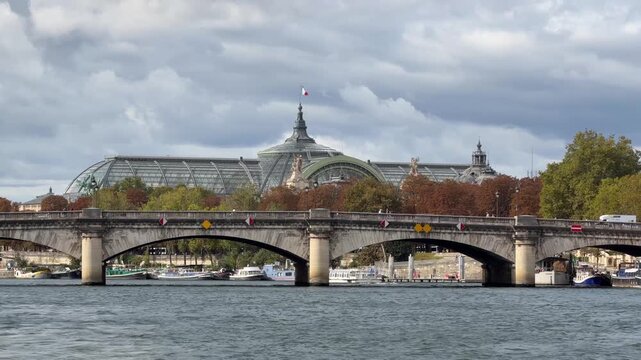 Overcast autumn view of the Grand Palais and Pont de la Concorde bridge along the Seine River in Paris, France, with colorful fall foliage and passing traffic. 15474  